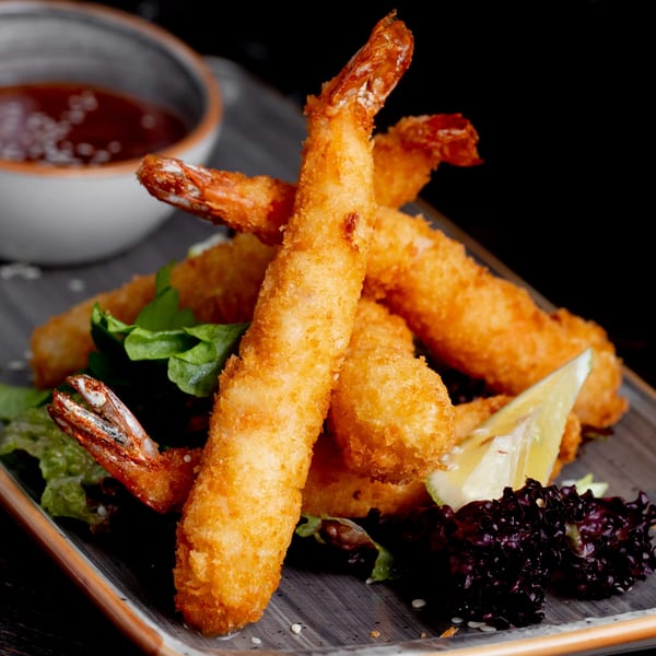 Crispy fried shrimp tempura with lettuce, a lemon wedge, and a side of dipping sauce.
