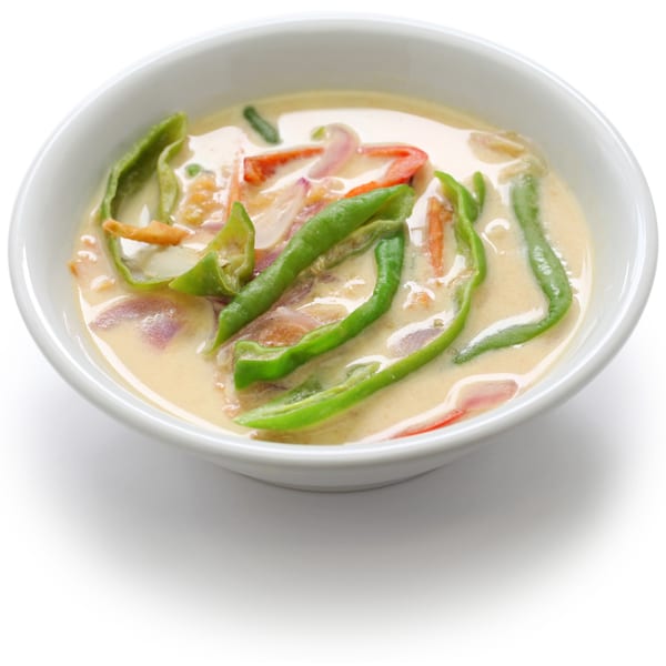 A white bowl filled with creamy Indian curry, green peppers, red onions, and carrots.
